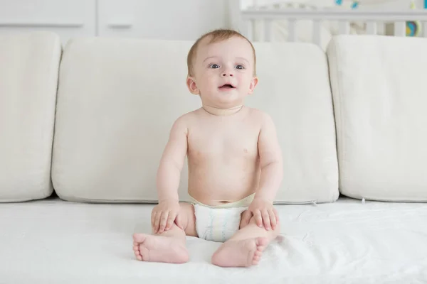 性格开朗的男婴，坐在床上的尿布 — 图库照片