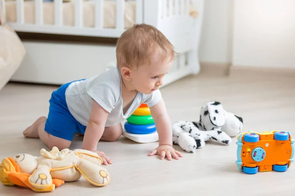 Ładny chłopczyk bawi się zabawkami kolorowe na podłodze w pokoju dziennym — Zdjęcie stockowe