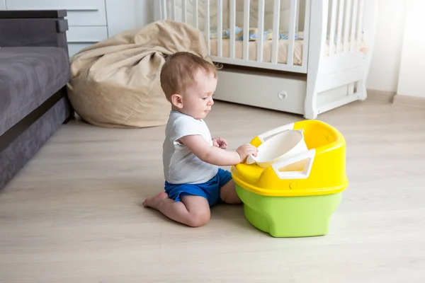 Baby pojke sitter på golvet och tittar på potta — Stockfoto