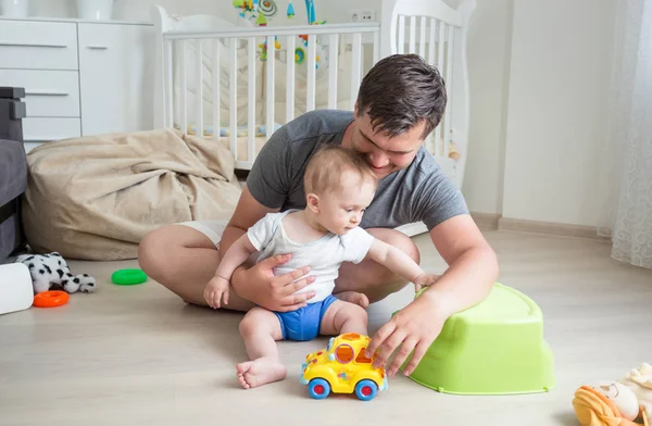 Padre y su bebé jugando con el coche de juguete en el suelo en casa — Foto de Stock