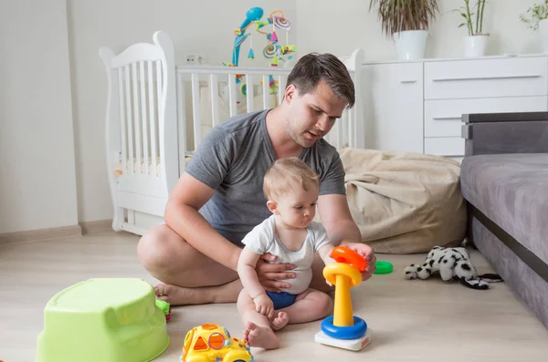 Отец сидит на полу со своим ребенком и играет с игрушками — стоковое фото