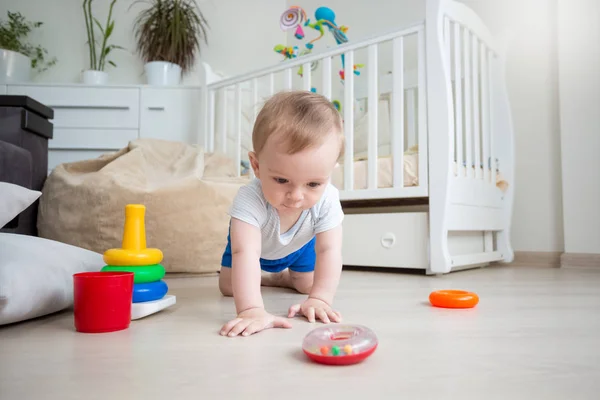 Baby boy playing on floor with colorful rings from toy pyramid t — Stock Photo, Image