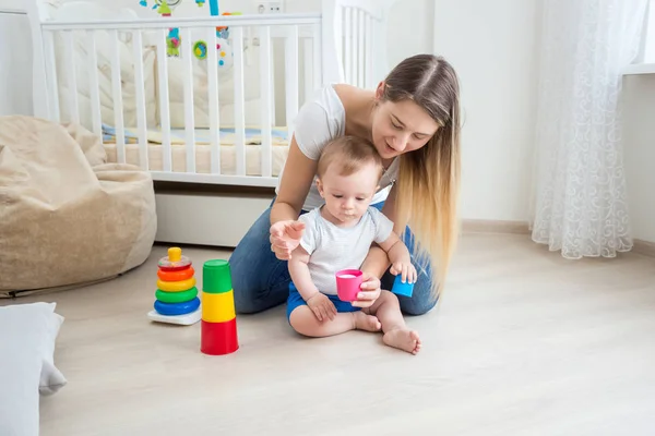Young mother playing and teaching her baby boy on floor at livin — Stock Photo, Image