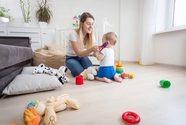 Joven madre jugando a su hijo pequeño y fingiendo hablar por phon — Foto de Stock