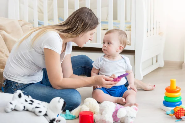 Όμορφη νεαρή μητέρα παίζει με το μωρό της στο πάτωμα — Φωτογραφία Αρχείου