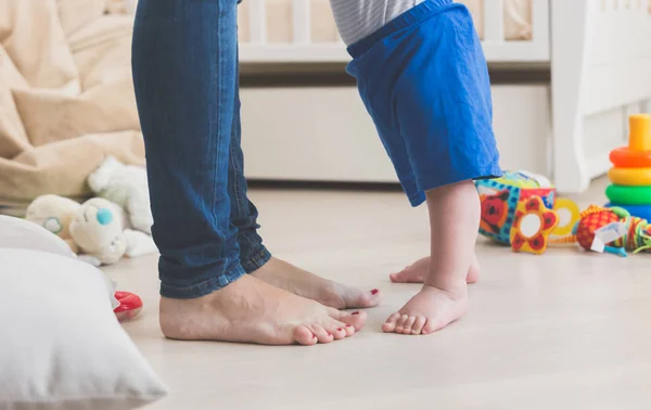 Nahaufnahme der kleinen Babyfüße auf dem Boden neben den Füßen der Mutter — Stockfoto