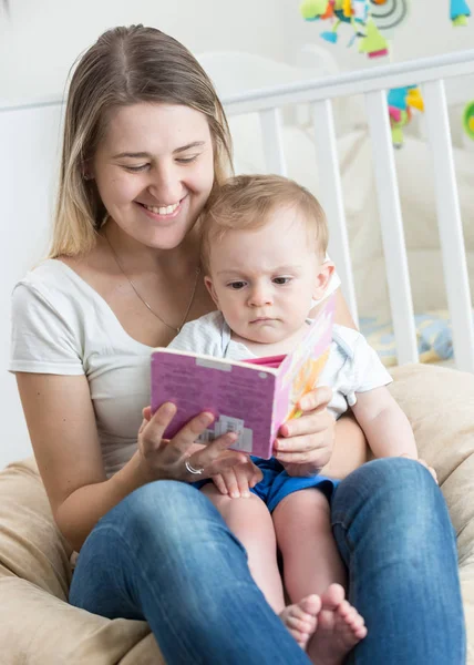 Beautiful cheerful mother reading book with her baby boy