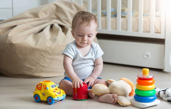 Bonito menino criança brincando com brinquedos coloridos no chão na vida r — Fotografia de Stock