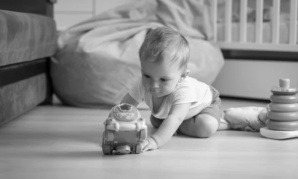 Black and white image of baby boy crawling on floor and reaching — Stock Photo, Image