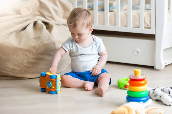 Menino brincando no chão com carro de brinquedo colorido — Fotografia de Stock