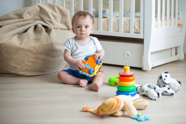Szczęśliwe dziecko chłopiec bawi się zabawkami na piętrze w sypialni — Zdjęcie stockowe