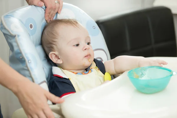 Niño de 9 meses sentado en silla alta y buscando un plato —  Fotos de Stock
