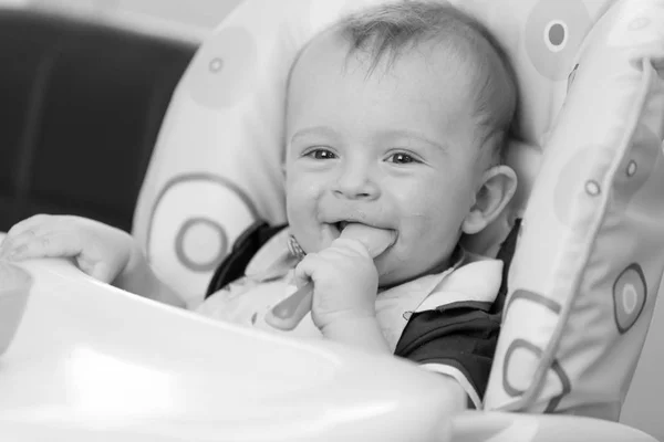 Retrato monocromo de bebé sonriente y juguetón comiendo de cuchara en —  Fotos de Stock