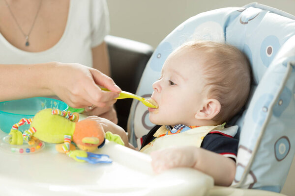 Portrait of baby boy eating in highchair at kitchen