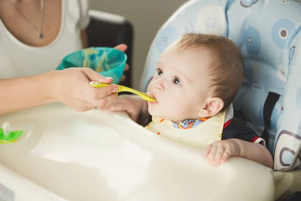 Mother giving porridge to her baby boy from plastic spoon — Stock Photo, Image