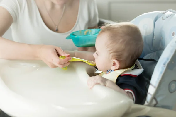 Woman feeding her baby from spoon with apple sauce — Stock Photo, Image