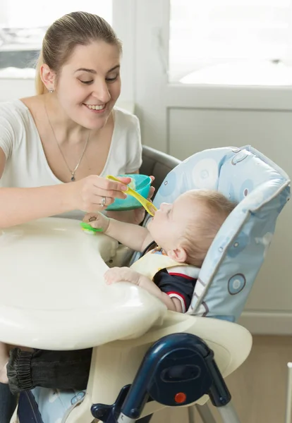 Joven madre alimentación bebé niño en silla alta — Foto de Stock