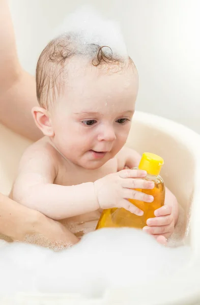 Jovem mãe tomando banho seu bebê menino no banho — Fotografia de Stock