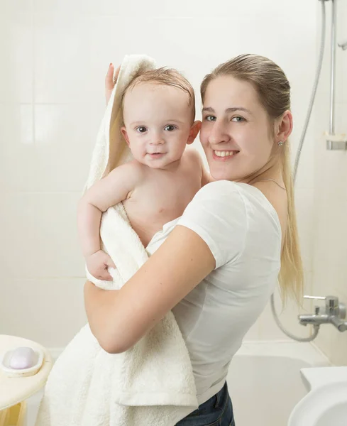 Mère souriante heureuse essuyant son bébé avec une serviette après avoir eu une batte — Photo