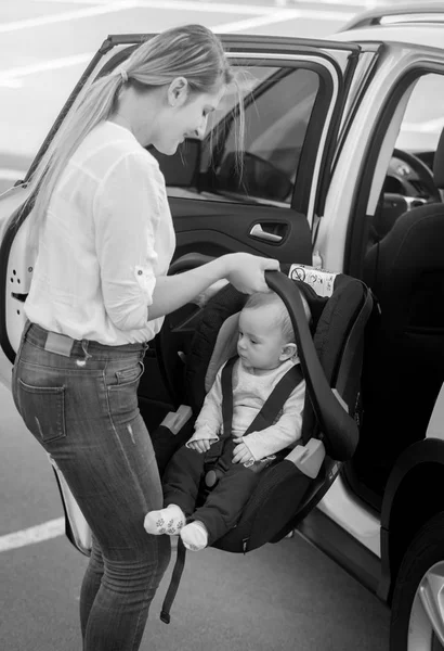 Imagen en blanco y negro de la madre joven poniendo silla de coche con ella — Foto de Stock