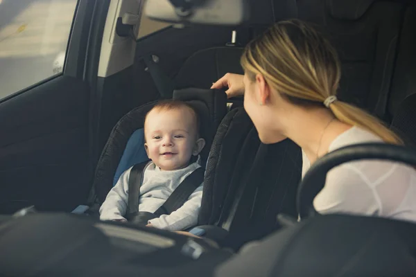 कार फ्रंट सीट पर बैठे बच्चे को देखते हुए माँ का चित्र — स्टॉक फ़ोटो, इमेज