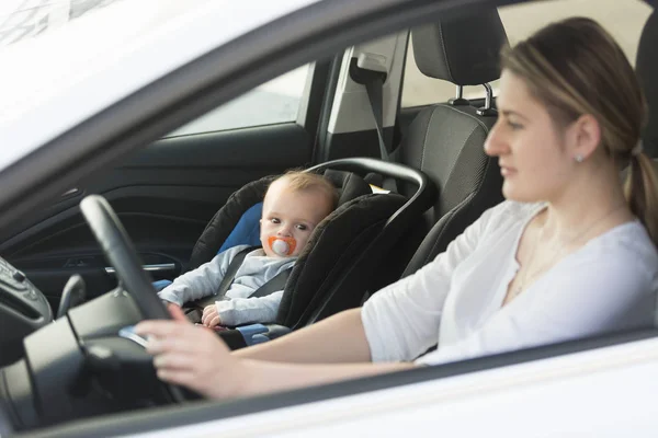 Vrouw die auto rijden met baby zittend op de voorste zitplaats — Stockfoto