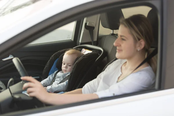 Joven madre conduciendo coche con su bebé niño sentado en coche en bab —  Fotos de Stock