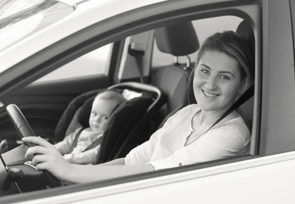 Черно-белый портрет молодой мамы за рулем автомобиля — стоковое фото