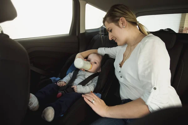 Retrato de una joven madre sonriente alimentando al bebé en el coche —  Fotos de Stock