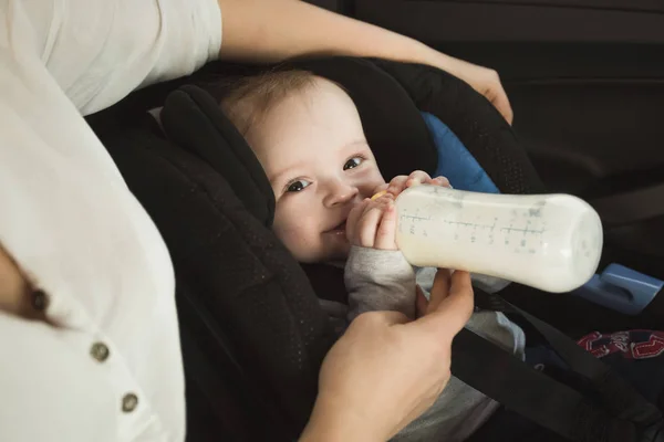 Retrato del niño bebiendo leche del biberón en el asiento trasero del coche —  Fotos de Stock