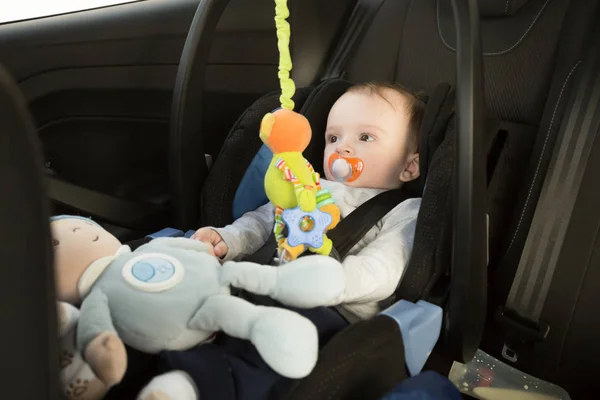 Niño sentado en el asiento del coche y jugando con juguetes —  Fotos de Stock