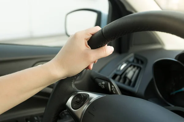 Closeup of female hand holding car steering wheel — Stock Photo, Image