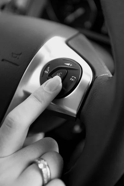 Black and white photo of female driver pressing button on steeri — Stock Photo, Image