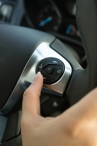 Closeup of driver pressing phone button on car steering wheel — Stock Photo, Image