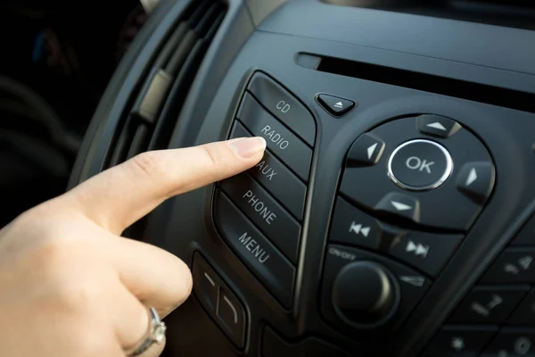 Primer plano de dedo femenino pulsando el botón de radio en el control del coche pa — Foto de Stock