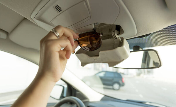Woman taking sunglasses out of special car compartment