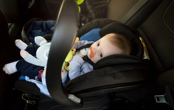 Lindo niño sentado en el asiento de seguridad del bebé en el coche — Foto de Stock