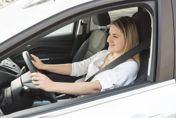 Молодая улыбающаяся женщина водит машину и смотрит на дорогу — стоковое фото