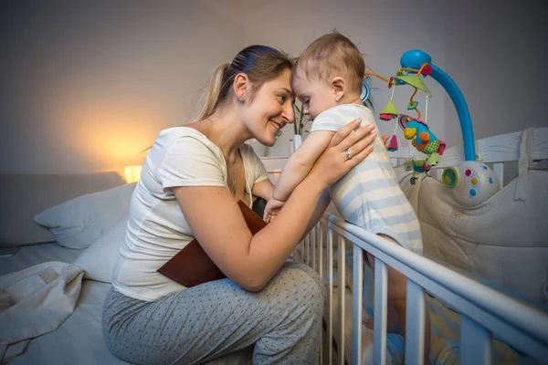 S에 가기 전에 침대에서 그녀의 아기를 보고 행복 한 젊은 어머니 — 스톡 사진