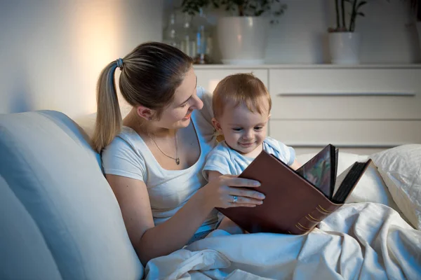 Beautiful smiling mother reading story to her baby boy before go — Stock Photo, Image