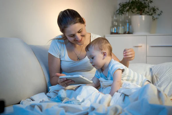 Niño sentado en la cama con la madre y el uso de la tableta digital en — Foto de Stock