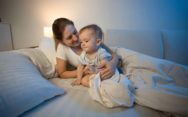 Bonito menino e sua mãe na cama no final da noite — Fotografia de Stock