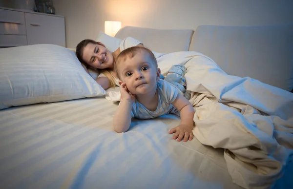 Rozkošný chlapeček ležel na posteli vedle jeho matka snaží slee — Stock fotografie