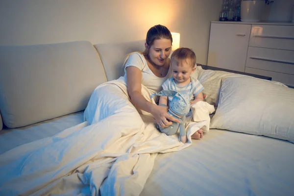 Baby boy playing on bed at late night with his mother — Stock Photo, Image