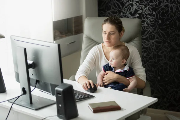 若い母親は、自宅オフィスで仕事と彼女の赤ちゃんの世話 — ストック写真