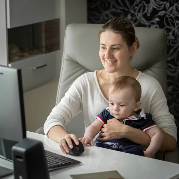 Mulher trabalhando em casa no computador e cuidando de seu bebê — Fotografia de Stock