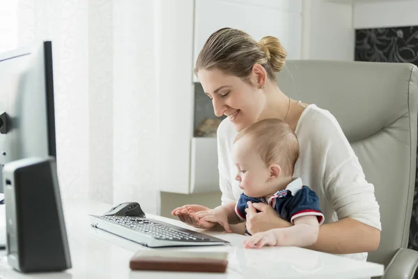 Jovem mulher com bebê trabalhando em casa e usando computador — Fotografia de Stock