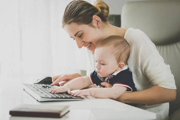 Sorrindo empresária posando com seu bebê no escritório — Fotografia de Stock