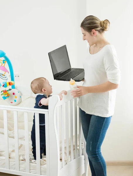 Mujer joven con bebé trabajando en casa en el ordenador portátil — Foto de Stock