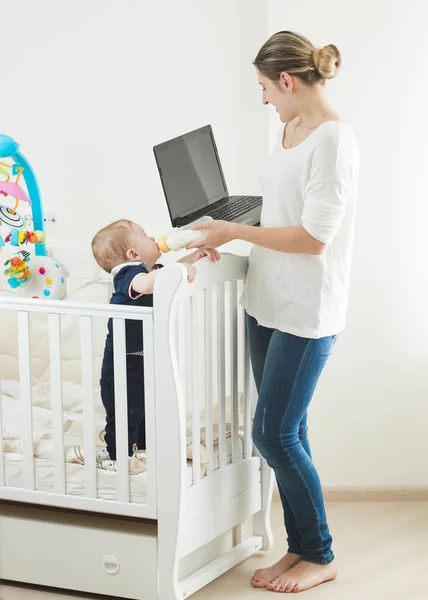 Kobieta pracuje na laptopie i dbanie o jej dziecko — Zdjęcie stockowe